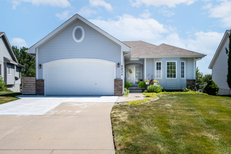 Blue ranch style home with spotless landscaping in front lawn.