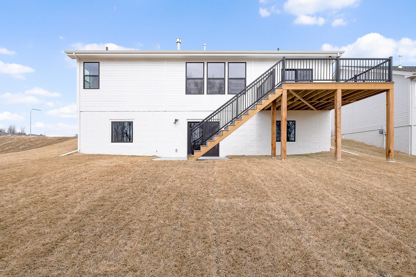 Backyard exterior, deck, and home windows seen from afar on a winter yellow-grass lawn.