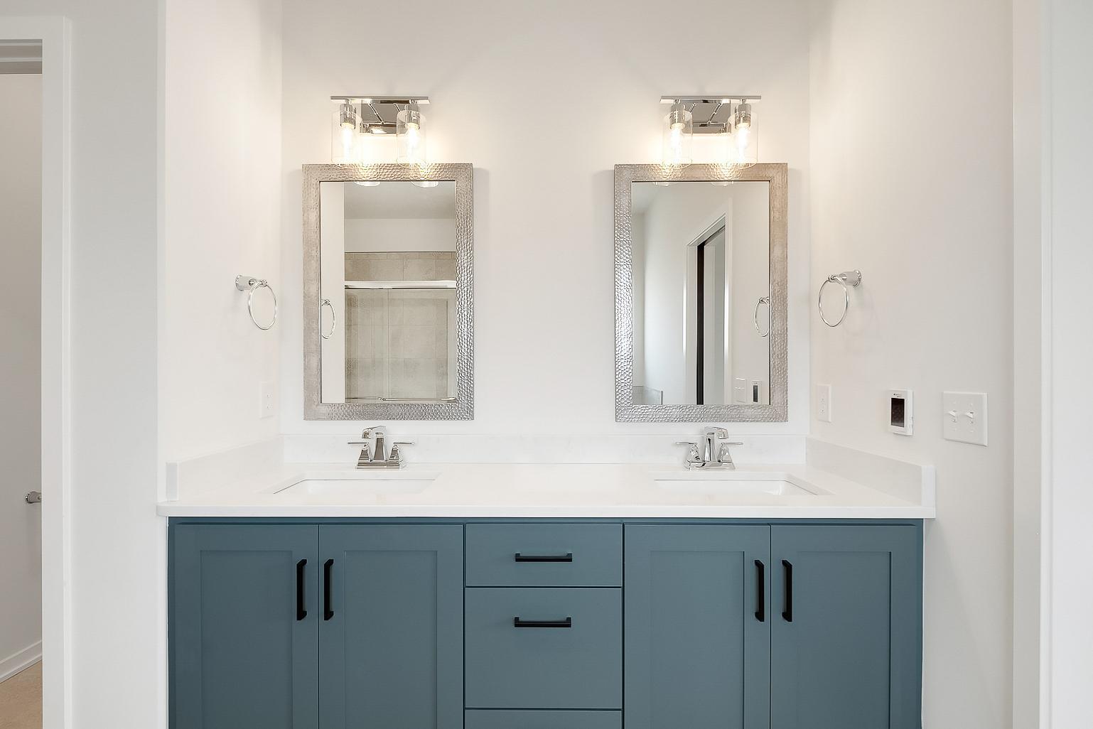 Two sinks on a grey and white vanity with silver accented mirrors, lights, and fixtures.