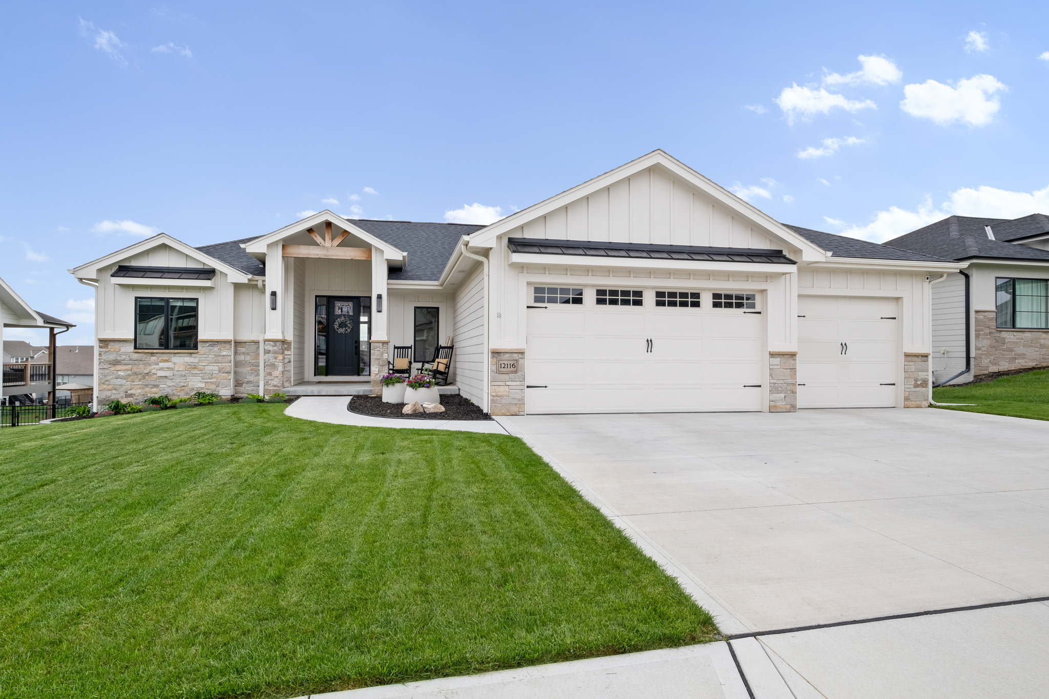 A white ranch home's front door, front yard, driveway, and garage.