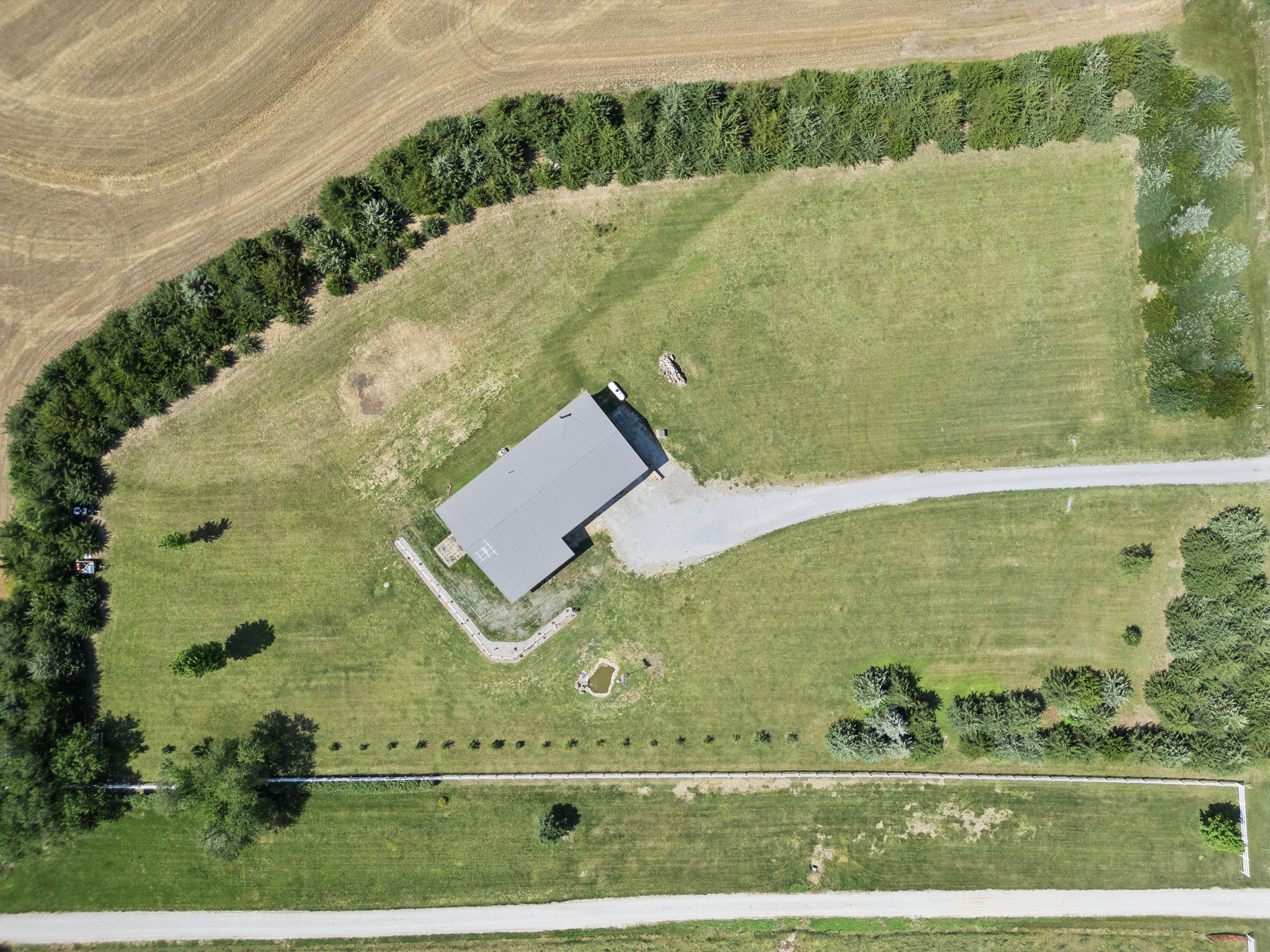 An overhead drone image of a rural property's layout with a driveway, home, and trees surrounding the land.