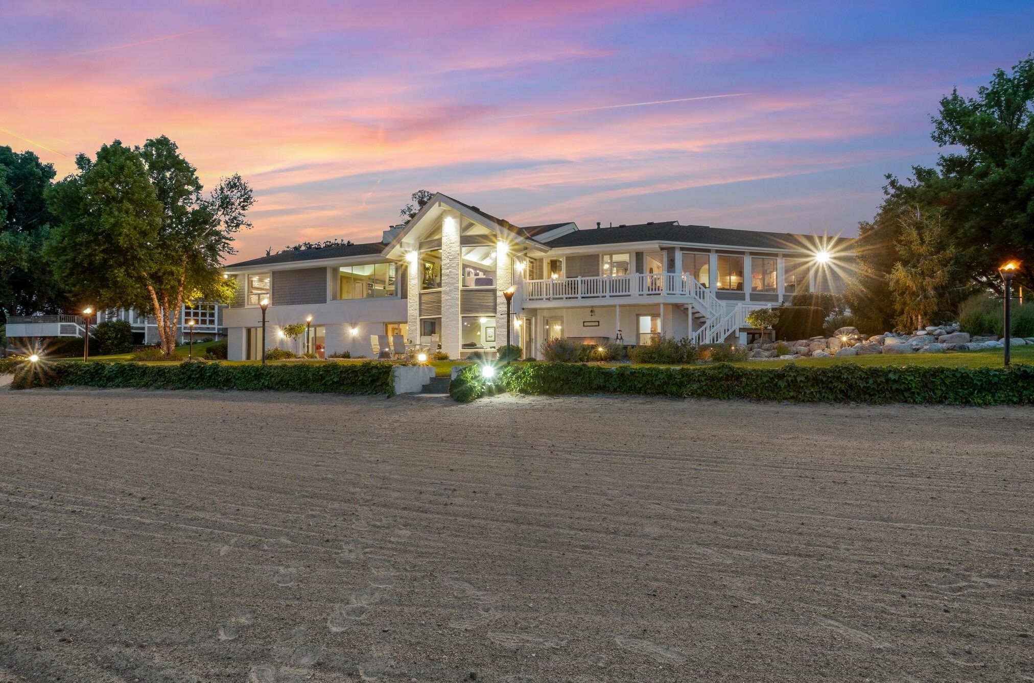 A real twilight image of a beachfront property with it's exterior lights on at sunset.